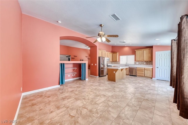 3604 Cantura Crest Ct, North Las Vegas, NV 89031 - kitchen with stainless steel appliances, ceiling fan, arched walkways, a kitchen island, and light countertops