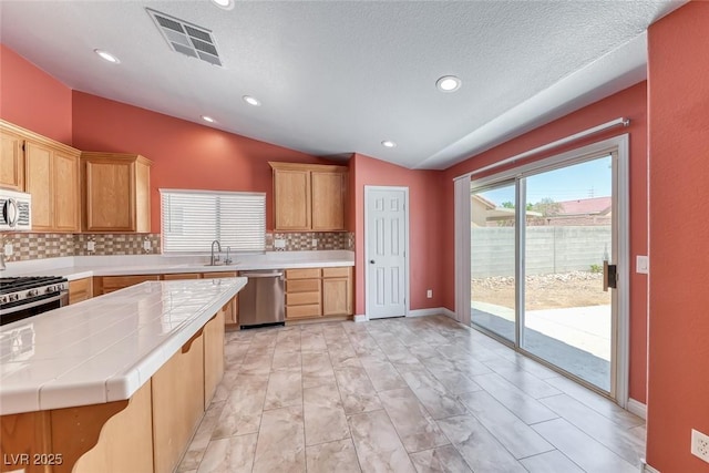 3604 Cantura Crest Ct, North Las Vegas, NV 89031 - kitchen with lofted ceiling, tasteful backsplash, appliances with stainless steel finishes, tile countertops, and recessed lighting