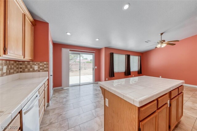 3604 Cantura Crest Ct, North Las Vegas, NV 89031 - kitchen with white dishwasher, tile countertops, decorative backsplash, ceiling fan, and a center island