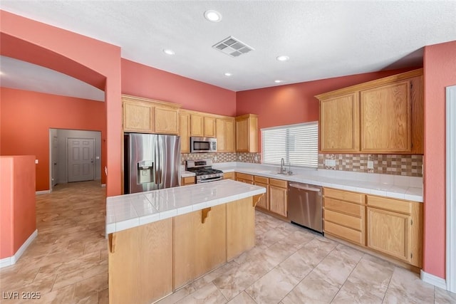 3604 Cantura Crest Ct, North Las Vegas, NV 89031 - kitchen featuring appliances with stainless steel finishes, tile counters, a kitchen island, tasteful backsplash, and recessed lighting