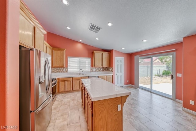 3604 Cantura Crest Ct, North Las Vegas, NV 89031 - kitchen with stainless steel appliances, tile counters, tasteful backsplash, vaulted ceiling, and a kitchen island