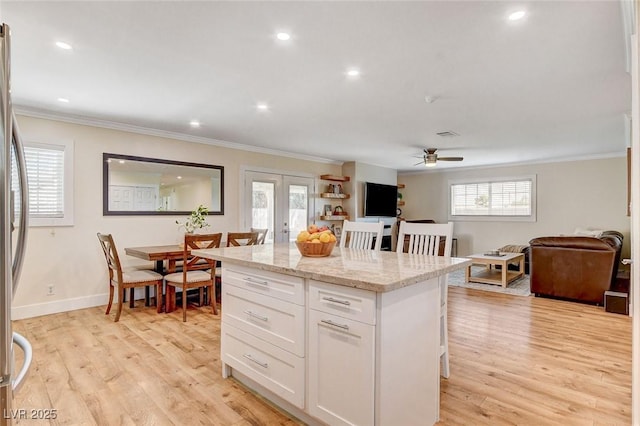 925 Alan Shepard St, Las Vegas, NV 89145 - kitchen with ornamental molding, a ceiling fan, white cabinets, a kitchen island, and a breakfast bar