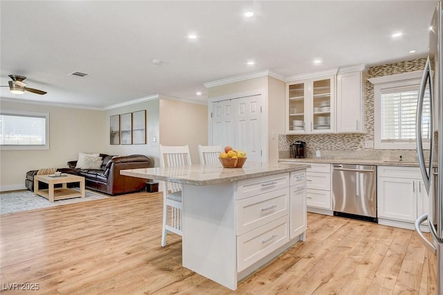 925 Alan Shepard St, Las Vegas, NV 89145 - kitchen featuring appliances with stainless steel finishes, ornamental molding, a kitchen breakfast bar, plenty of natural light, and light wood-style flooring