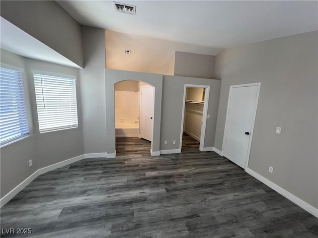 3238 Canyon Terrace Dr, Laughlin, NV 89029 - unfurnished bedroom with vaulted ceiling, arched walkways, dark wood-style flooring, a spacious closet, and ensuite bathroom