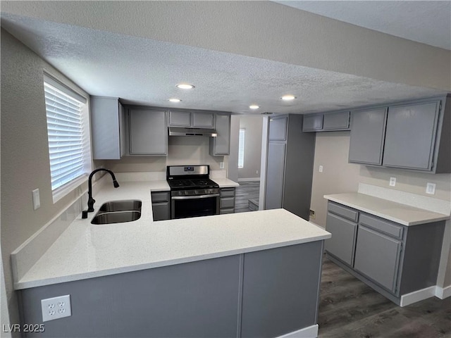 3238 Canyon Terrace Dr, Laughlin, NV 89029 - kitchen featuring gas range, gray cabinetry, under cabinet range hood, a peninsula, and a textured ceiling