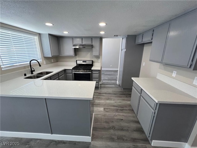 3238 Canyon Terrace Dr, Laughlin, NV 89029 - kitchen featuring gray cabinets, stainless steel gas range, under cabinet range hood, a textured ceiling, and dark wood finished floors