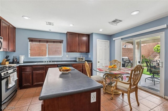 11620 Longhirst Hall Ln, Las Vegas, NV 89138 - kitchen with stainless steel gas stove, dark countertops, light tile patterned flooring, a center island, and recessed lighting