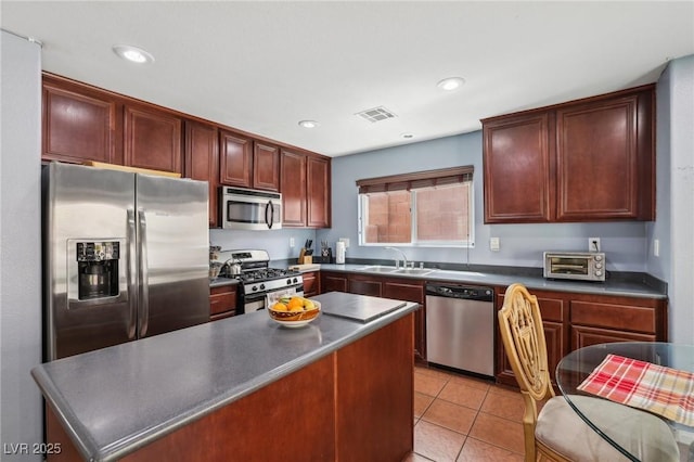 11620 Longhirst Hall Ln, Las Vegas, NV 89138 - kitchen with appliances with stainless steel finishes, dark countertops, light tile patterned floors, a kitchen island, and recessed lighting