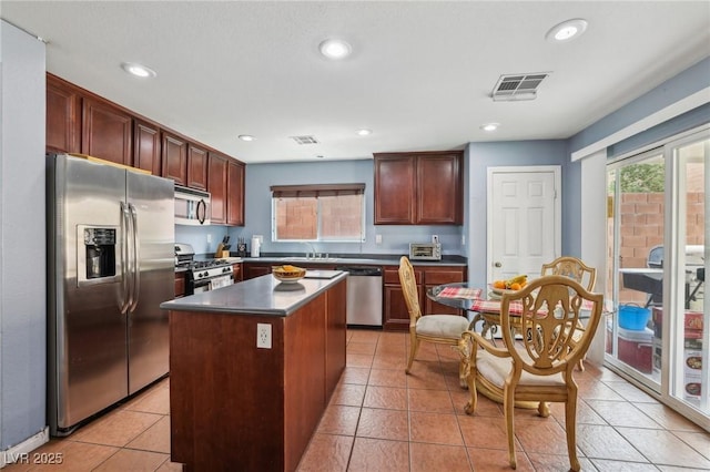 11620 Longhirst Hall Ln, Las Vegas, NV 89138 - kitchen with stainless steel appliances, a kitchen island, recessed lighting, light tile patterned floors, and dark countertops