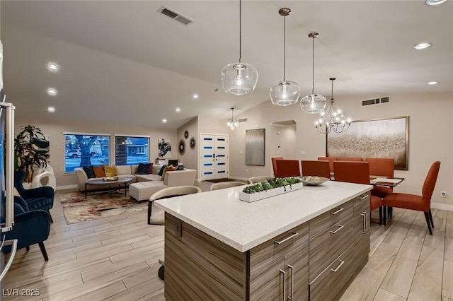 6316 Bluejay Way, Las Vegas, NV 89146 - kitchen with light countertops, a kitchen island, light wood-style flooring, open floor plan, and hanging light fixtures
