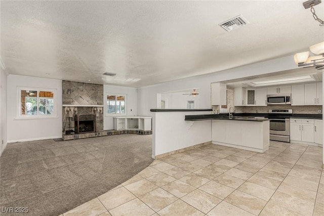 1393 Calmview Pl, Las Vegas, NV 89110 - kitchen featuring appliances with stainless steel finishes, dark countertops, healthy amount of natural light, and light colored carpet