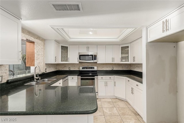 1393 Calmview Pl, Las Vegas, NV 89110 - kitchen with stainless steel appliances, a raised ceiling, white cabinets, a peninsula, and glass insert cabinets