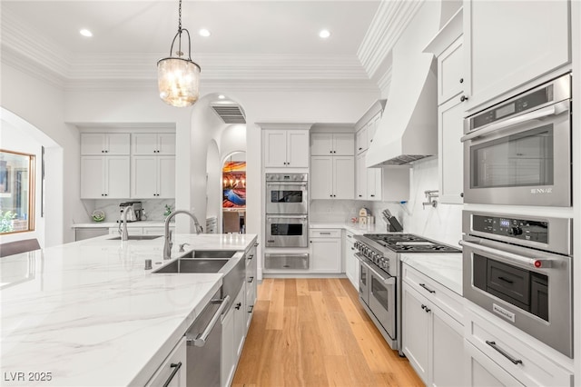 38 Pebble Dunes Ct, Las Vegas, NV 89141 - kitchen with stainless steel appliances, a warming drawer, arched walkways, wall chimney range hood, and tasteful backsplash
