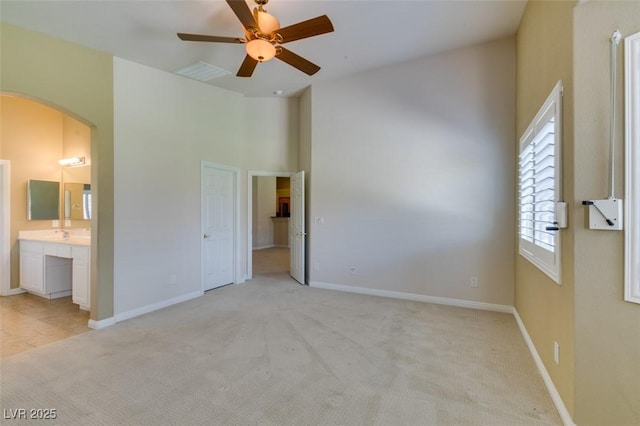 8204 Turbys Treehouse Pl, Las Vegas, NV 89131 - unfurnished bedroom featuring arched walkways, light colored carpet, ensuite bath, a towering ceiling, and a ceiling fan