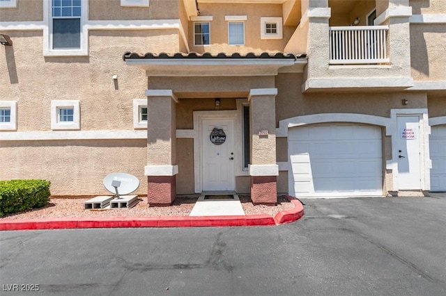 5855 Valley Dr Unit 2092, North Las Vegas, NV 89031 - doorway to property with a garage, stucco siding, a balcony, and asphalt driveway