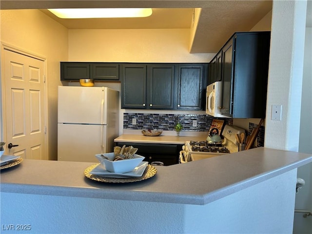 5855 Valley Dr Unit 2092, North Las Vegas, NV 89031 - kitchen featuring white appliances, tasteful backsplash, and a peninsula