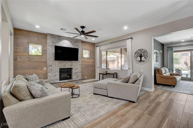 2333 Indigo Island St, Henderson, NV 89044 - living room featuring ceiling fan, light wood-type flooring, wood walls, plenty of natural light, and a fireplace