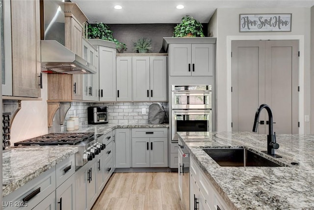 2333 Indigo Island St, Henderson, NV 89044 - kitchen with wall chimney exhaust hood, appliances with stainless steel finishes, recessed lighting, light wood-style flooring, and decorative backsplash