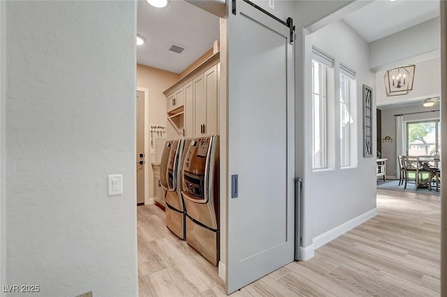 2333 Indigo Island St, Henderson, NV 89044 - washroom with washing machine and clothes dryer, cabinet space, a barn door, a chandelier, and light wood finished floors