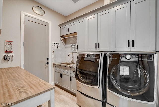 2333 Indigo Island St, Henderson, NV 89044 - laundry area featuring washing machine and clothes dryer, cabinet space, and light wood-style flooring