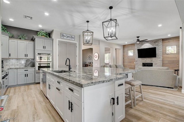 2333 Indigo Island St, Henderson, NV 89044 - kitchen with stainless steel double oven, ceiling fan, recessed lighting, light wood finished floors, and a breakfast bar