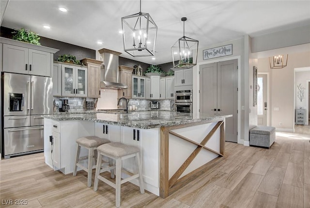2333 Indigo Island St, Henderson, NV 89044 - kitchen with stainless steel appliances, a chandelier, wall chimney exhaust hood, tasteful backsplash, and recessed lighting