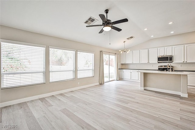 9514 Teton Vista Ave, Las Vegas, NV 89117 - kitchen featuring stainless steel microwave, a chandelier, ceiling fan, lofted ceiling, and white cabinetry