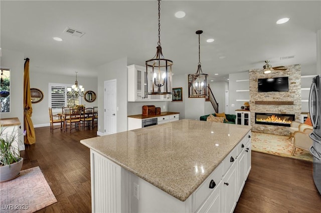 326 Caneflower Ct, North Las Vegas, NV 89031 - kitchen featuring a chandelier, a stone fireplace, dark wood finished floors, a kitchen island, and glass insert cabinets