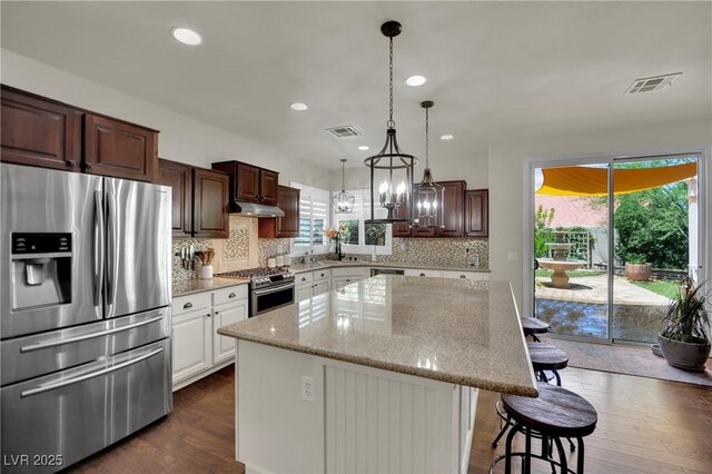 326 Caneflower Ct, North Las Vegas, NV 89031 - kitchen featuring stainless steel appliances, under cabinet range hood, a center island, backsplash, and a breakfast bar