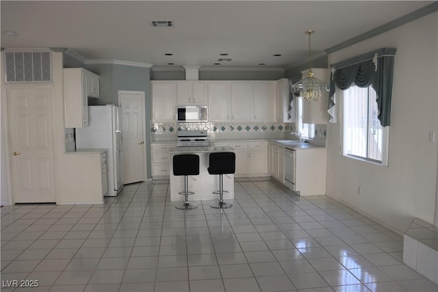 8982 Emerald Waters Ct, Las Vegas, NV 89147 - kitchen featuring white appliances, a breakfast bar area, backsplash, ornamental molding, and a center island