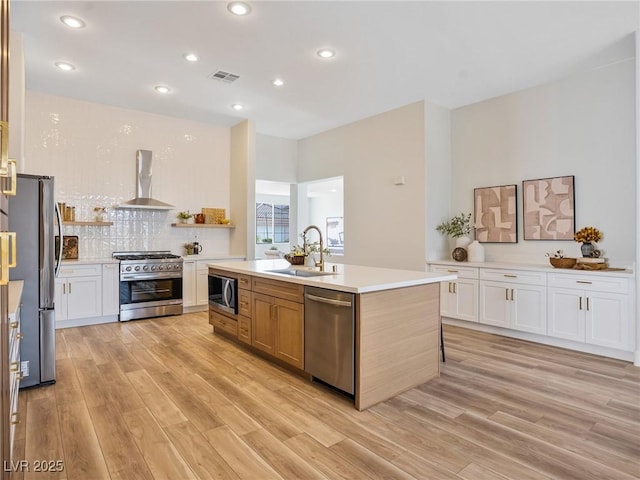 4314 Livorno Ave, Las Vegas, NV 89141 - kitchen with appliances with stainless steel finishes, wall chimney range hood, light wood-style flooring, light countertops, and decorative backsplash
