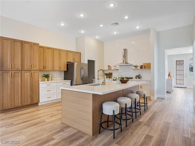 4314 Livorno Ave, Las Vegas, NV 89141 - kitchen with freestanding refrigerator, wall chimney exhaust hood, light wood-style floors, light countertops, and recessed lighting