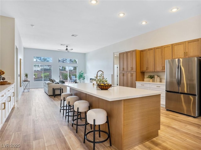 4314 Livorno Ave, Las Vegas, NV 89141 - kitchen featuring freestanding refrigerator, light wood-type flooring, a kitchen breakfast bar, open floor plan, and recessed lighting