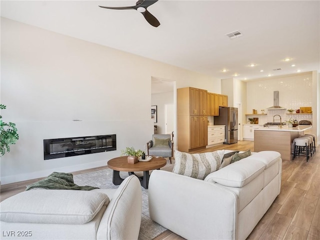 4314 Livorno Ave, Las Vegas, NV 89141 - living area featuring a ceiling fan, a glass covered fireplace, light wood-type flooring, and recessed lighting