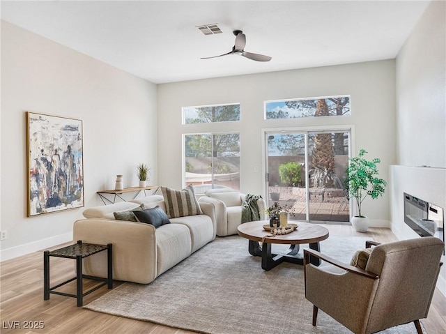 4314 Livorno Ave, Las Vegas, NV 89141 - living room featuring ceiling fan, healthy amount of natural light, light wood finished floors, and a glass covered fireplace