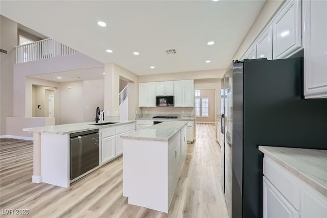 9272 W Viking Rd, Las Vegas, NV 89147 - kitchen with appliances with stainless steel finishes, white cabinets, light wood-style flooring, a peninsula, and a kitchen island