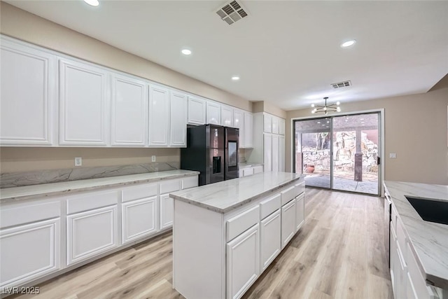 9272 W Viking Rd, Las Vegas, NV 89147 - kitchen with black fridge with ice dispenser, white cabinetry, a chandelier, light wood-type flooring, and recessed lighting