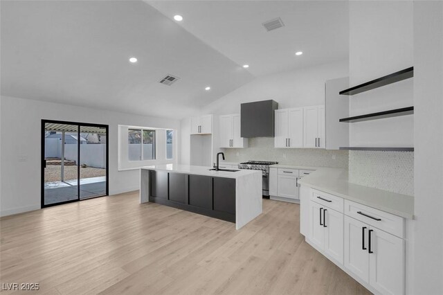 363 El Pico Dr, Henderson, NV 89014 - kitchen with open shelves, stainless steel stove, wall chimney exhaust hood, a center island with sink, and backsplash
