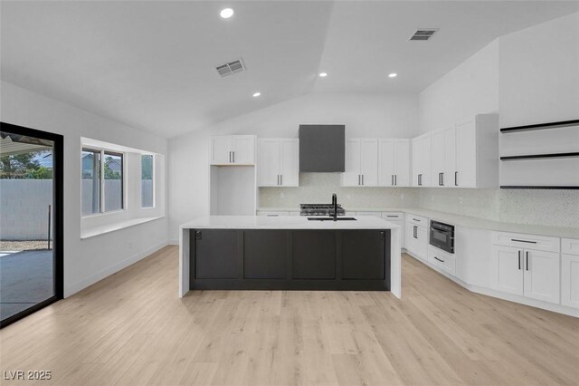 363 El Pico Dr, Henderson, NV 89014 - kitchen with wall chimney range hood, lofted ceiling, white cabinets, tasteful backsplash, and light countertops