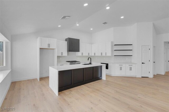363 El Pico Dr, Henderson, NV 89014 - kitchen featuring vaulted ceiling, white cabinetry, light wood-style flooring, light countertops, and a center island with sink