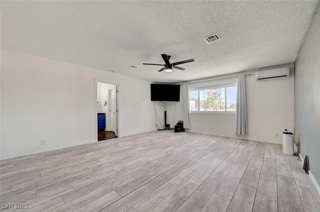 3917 Leon Ave, Las Vegas, NV 89130 - unfurnished living room featuring a wall mounted air conditioner, ceiling fan, light wood-style flooring, and a textured ceiling
