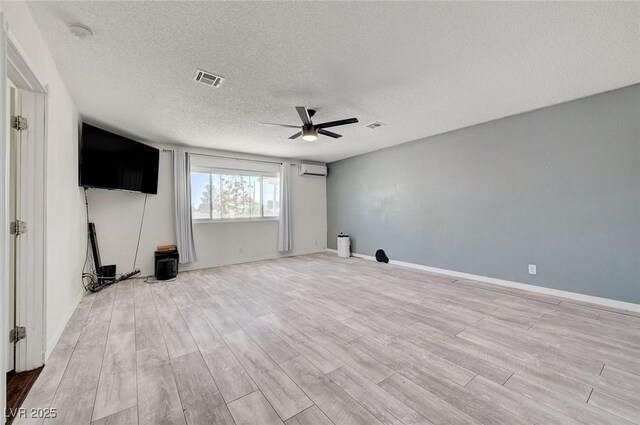 3917 Leon Ave, Las Vegas, NV 89130 - unfurnished living room with ceiling fan, a textured ceiling, a wall mounted air conditioner, and light wood-style flooring