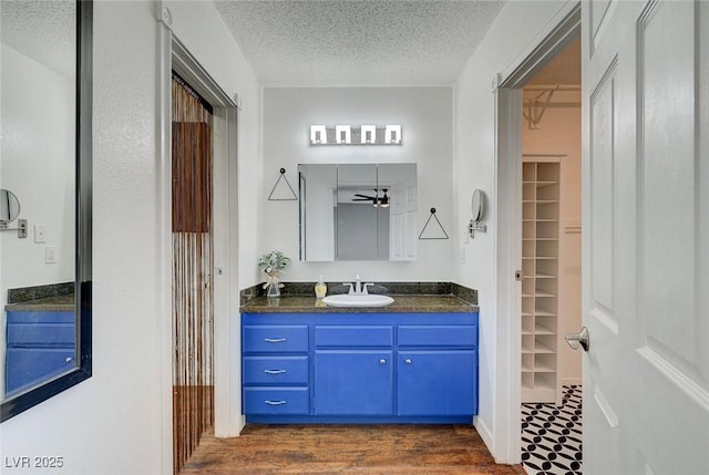 3917 Leon Ave, Las Vegas, NV 89130 - bathroom featuring a textured ceiling, vanity, a spacious closet, wood finished floors, and a ceiling fan
