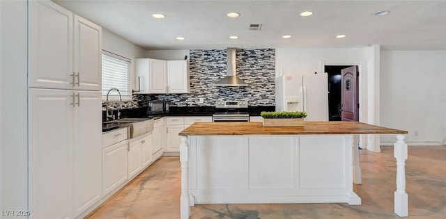 3917 Leon Ave, Las Vegas, NV 89130 - kitchen with wall chimney range hood, white refrigerator with ice dispenser, stainless steel range with electric cooktop, wooden counters, and finished concrete floors