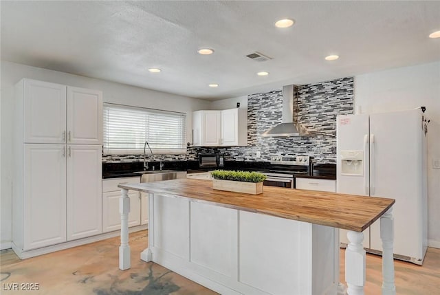 3917 Leon Ave, Las Vegas, NV 89130 - kitchen featuring wall chimney range hood, white refrigerator with ice dispenser, wooden counters, tasteful backsplash, and recessed lighting