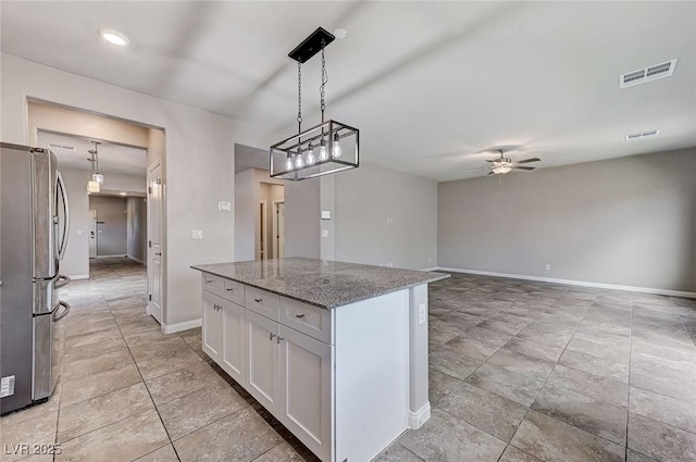 934 Twincrest Ave, North Las Vegas, NV 89032 - kitchen featuring freestanding refrigerator, a ceiling fan, white cabinets, light stone countertops, and a kitchen island