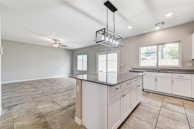 934 Twincrest Ave, North Las Vegas, NV 89032 - kitchen featuring white cabinetry, a kitchen island, dark stone countertops, ceiling fan, and hanging light fixtures