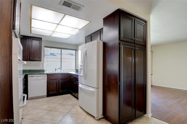 6822 Garden Grove Ave, Las Vegas, NV 89103 - kitchen with white appliances, light tile patterned floors, and dark brown cabinets