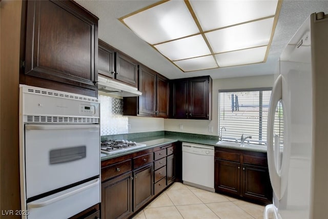 6822 Garden Grove Ave, Las Vegas, NV 89103 - kitchen with white appliances, a warming drawer, under cabinet range hood, dark brown cabinetry, and light tile patterned floors