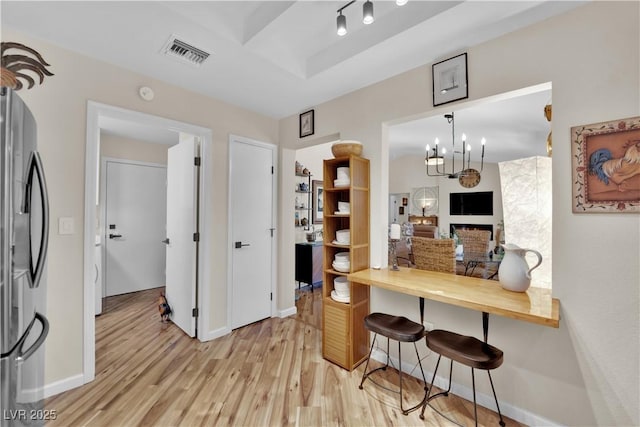 9237 Quail Ridge Dr, Las Vegas, NV 89134 - kitchen featuring freestanding refrigerator, light wood-style floors, a kitchen bar, a raised ceiling, and a chandelier